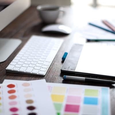 Shallow depth of field closeup of a graphic designer's workspace with a pen tablet, a computer and some color swatches