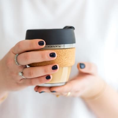 Woman hands hold reusable glass coffee cup. Sustainable living. Eco friendly, zero waste concept.